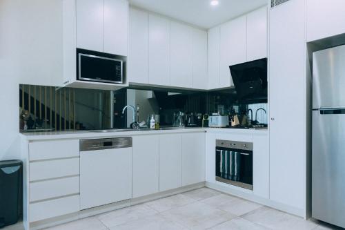 a white kitchen with white cabinets and a microwave at ‘The Lumos’ Designer home Close to Olympic Park in Sydney