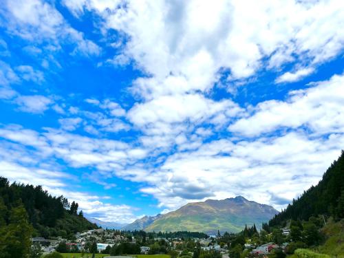 a cloudy sky over a town and a mountain at Queenstown Retreat in Queenstown