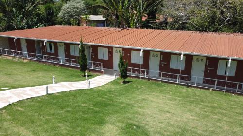 a building with a red roof and a grass yard at Pousada Villa São Francisco in Boituva