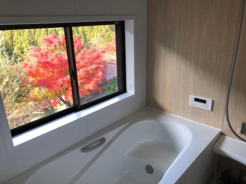 baño con bañera blanca y ventana en Kazuraya en Miyoshi