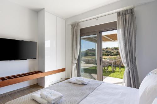 a bedroom with a bed and a tv and a balcony at EVELAND ACCESSIBLE VILLAS in Sfakaki