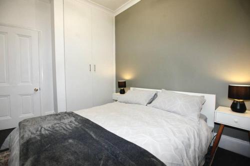 a white bedroom with a white bed and a lamp at The Pavilion End - Central Paddington Apartment in Sydney