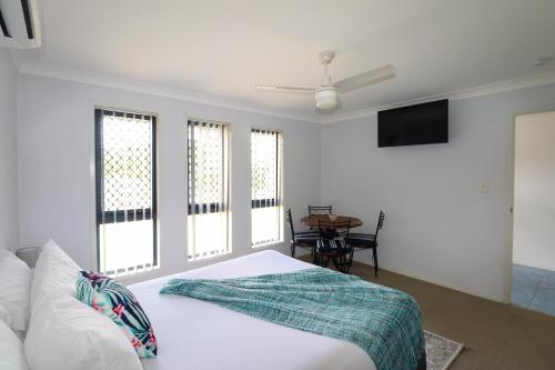Schlafzimmer mit einem Bett, einem Tisch und Fenstern in der Unterkunft BLK Stays Guest House Deluxe Units Morayfield in Morayfield