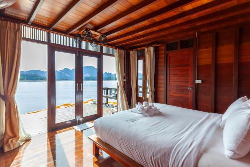 a bedroom with a bed with a view of the water at 500 Rai Floating Resort in Ratchaprapha