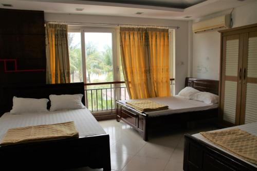a bedroom with two beds and a balcony at Catba Beach House in Cat Ba