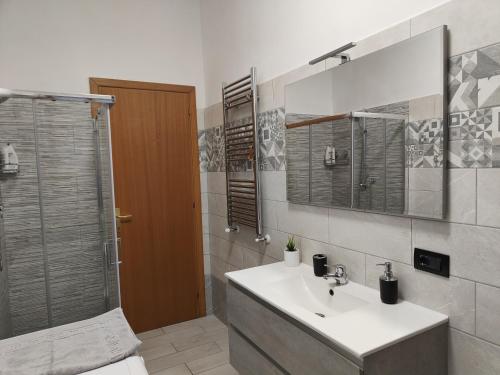 ein Bad mit einem Waschbecken und einer Dusche mit einem Spiegel in der Unterkunft Casa Trezza in Latina