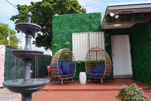 zwei Stühle und ein Vogelkäfig neben einem Brunnen in der Unterkunft Art Gardens Wynwood concept in Miami
