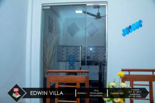 Zimmer mit einer Glastür mit 2 Stühlen und einem Tisch in der Unterkunft Edwin Villa in Trincomalee