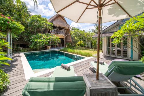 a pool with chairs and an umbrella next to a house at Villa Kasih Lembongan in Nusa Lembongan