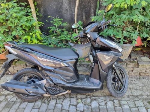a motorcycle parked on the street next to some plants at Suci's Friendly Apartments in Mataram