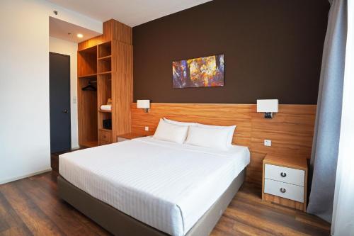 a bedroom with a white bed with a wooden headboard at Sunway Onsen Hospitality Suites in Ipoh