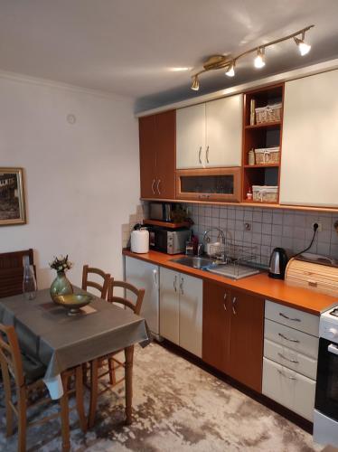 a kitchen with wooden cabinets and a table with chairs at Apartman Royal Vlašić in Vlasic
