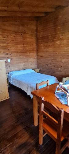 1 dormitorio con 1 cama y 1 mesa en una cabaña en Cabañas Tres Pinos en Sierra de la Ventana