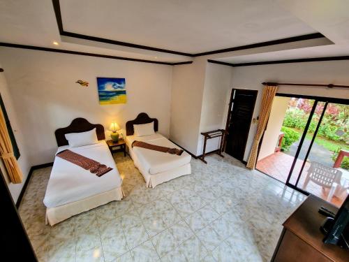 a bedroom with two beds and a balcony at Jasmin Resort - SHA Plus in Khao Lak