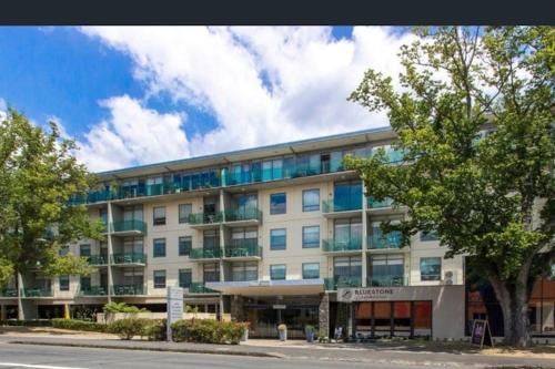 a large white building with trees in front of it at Three bedroom apartment in Sebel complex- on site restaurant, room service, gym and parking in Launceston