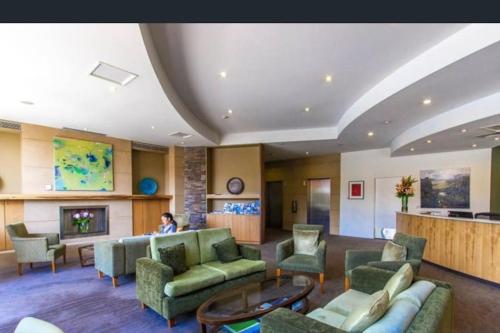 a lobby with couches and chairs and a fireplace at Three bedroom apartment in Sebel complex- on site restaurant, room service, gym and parking in Launceston