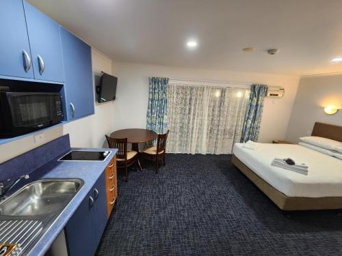 a hotel room with a kitchen and a bed and a table at Botany Palms Motel in Auckland