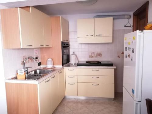 a kitchen with white cabinets and a sink and a refrigerator at Chez Papi - A 5 min da piste da Sci e Stazione CIR VDA AO 0013 in Aosta