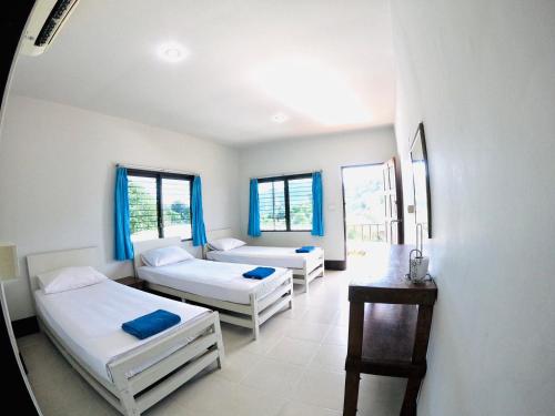 2 łóżka w pokoju z niebieskimi zasłonami w obiekcie JR&GYM Resort w Ko Phi Phi