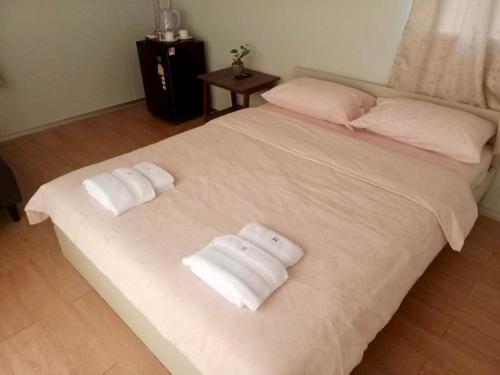 Una cama blanca con dos toallas plegables. en Homey Hut Ayutthaya en Phra Nakhon Si Ayutthaya