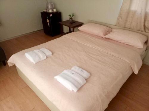 ein weißes Bett mit zwei gefalteten Handtüchern darauf in der Unterkunft Homey Hut Ayutthaya in Phra Nakhon Si Ayutthaya