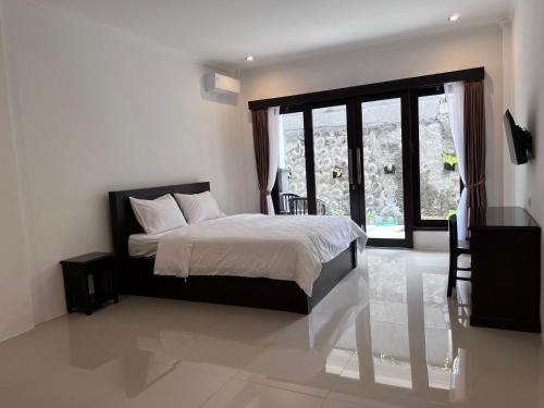 a bedroom with a bed and a large window at Green Hill Inn in Jimbaran