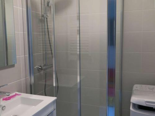une douche avec une porte vitrée à côté d'un lavabo dans l'établissement Appartement 3* à Perros-Guirec, plage à 50m, garage privé - FR-1-368-73, à Perros-Guirec