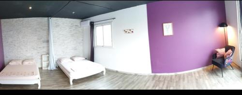 Cette chambre comprend 2 lits et un mur violet. dans l'établissement Lilie location langevin, à Saint-Joseph