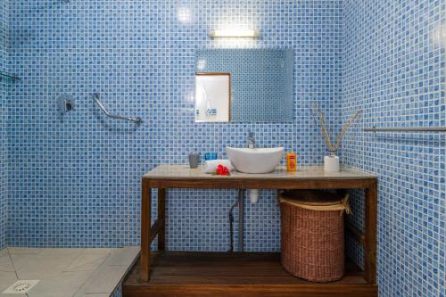 Baño de azulejos azules con lavabo y espejo en The Beach House, en Beau Vallon