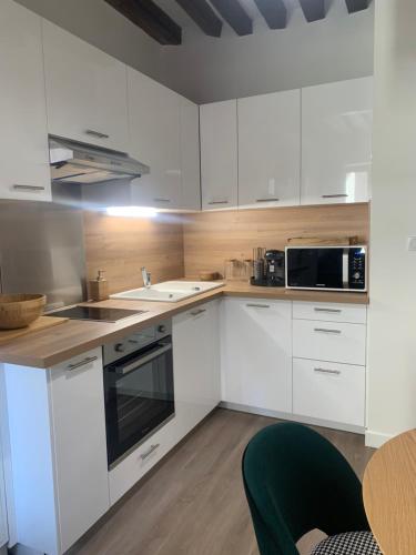 a kitchen with white cabinets and a black microwave at Appartement velouté in Dijon