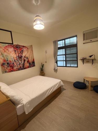 a bedroom with a bed and a painting on the wall at Nuan Hostel in Xiaoliuqiu
