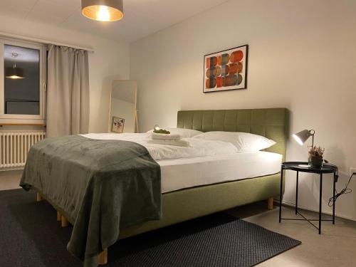 a bedroom with a large bed with a green headboard at Comfort 1 and 2BDR Apartment close to Zurich Airport in Zürich