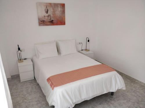 a bedroom with a white bed and two night stands at VV 'TIRBA' Precioso duplex a 1 minuto de la playa in Gran Tarajal