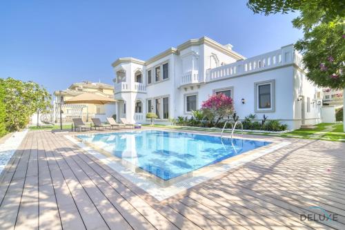 a house with a swimming pool in front of it at Signature 6BR Villa with Assistant Room and Private Pool in Frond F Palm Jumeirah by Deluxe Holiday Homes in Dubai