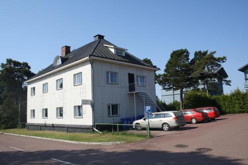 a white house with cars parked in a parking lot at Gästhem Kronan in Mariehamn