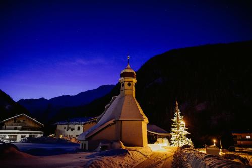 uma igreja com uma árvore de Natal na neve à noite em Alpenheim Simone em Sölden