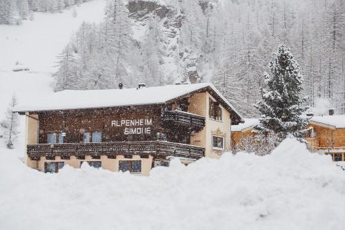 ein schneebedecktes Gebäude neben einem Baum in der Unterkunft Alpenheim Simone in Sölden