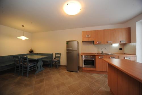 a kitchen with a table and a stainless steel refrigerator at Appartamenti Vegaia in Peio