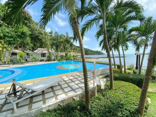 a swimming pool with palm trees and the ocean at White house bailan resort in Ko Chang