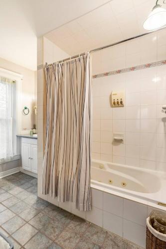 a bathroom with a tub and a shower curtain at Ye Olde Walkerville Bed & Breakfast in Windsor