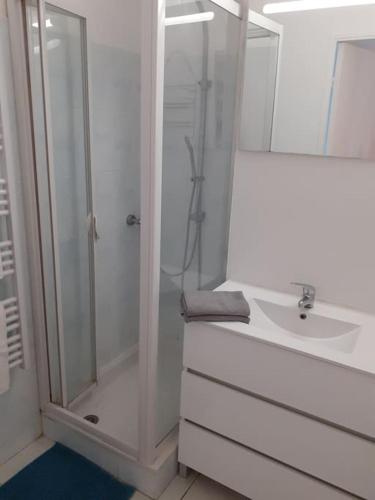 une salle de bain blanche avec une douche et un lavabo dans l'établissement Les Rivages de Rochelongues, T3, piscine, clim, parking, au Cap d'Agde