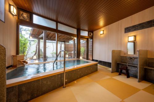 a bath tub in a room with a large window at Hohoemino Kuyufu Tsuruya in Tendo