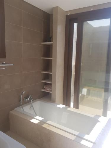 y baño con bañera y ventana. en Hawana Salalah Lake View Villa 22 en Salalah