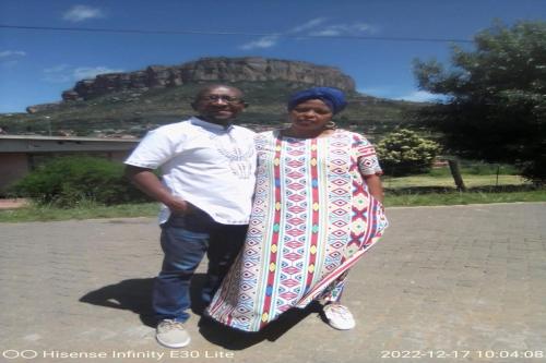 a man and a woman standing in front of a mountain at Maluti Backpackers in Phuthaditjhaba