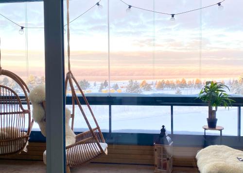 a room with two swinging chairs in front of a large window at SunBeach Apartment with seaview and sauna in Kalajoki