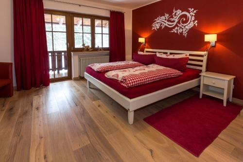 a bedroom with a bed with red walls and a red rug at Landhaus Gastager in Ruhpolding
