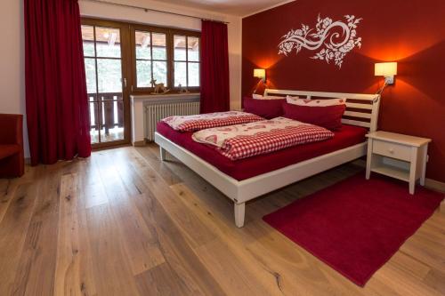 Schlafzimmer mit einem Bett mit roten Wänden und einem roten Teppich in der Unterkunft Landhaus Gastager in Ruhpolding