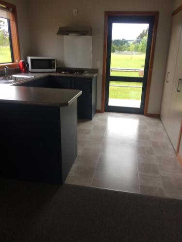 a room with a kitchen with a counter and a door at Acheron Cottages in Manapouri