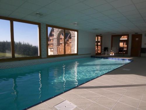 ein großer Pool in einem großen Zimmer mit Fenstern in der Unterkunft Lama-Gîte-des-Puys T3 Lamado vue époustouflante sud avec grande terrasse in Super Besse