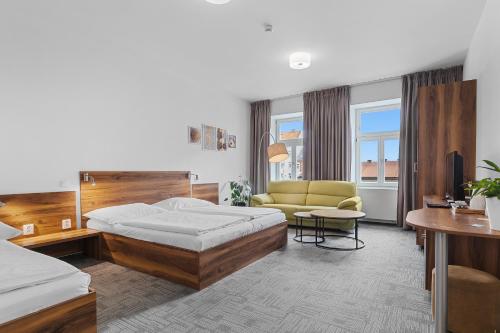 um quarto de hotel com uma cama e um sofá em Penzion Na Náměstí em Dvur Králové nad Labem